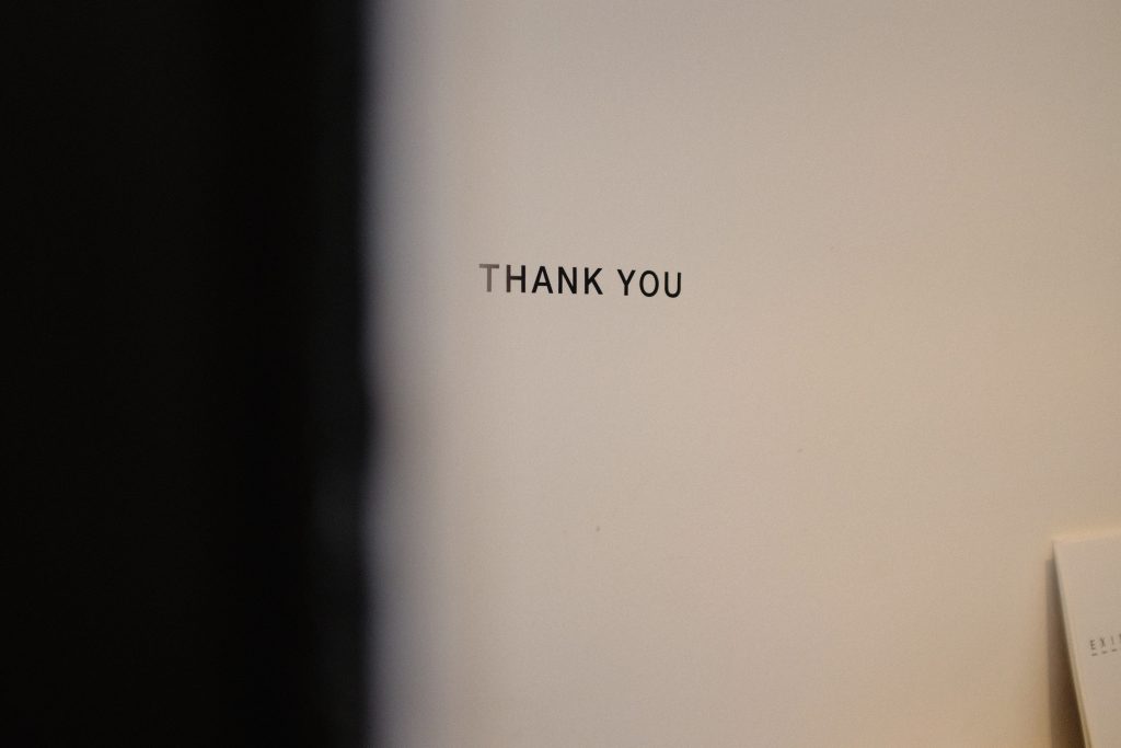 a thank you words written on typewriter letters on the white wall in a dim room