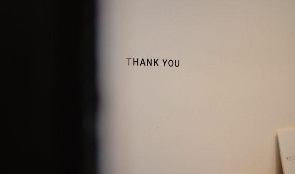 a thank you words written on typewriter letters on the white wall in a dim room