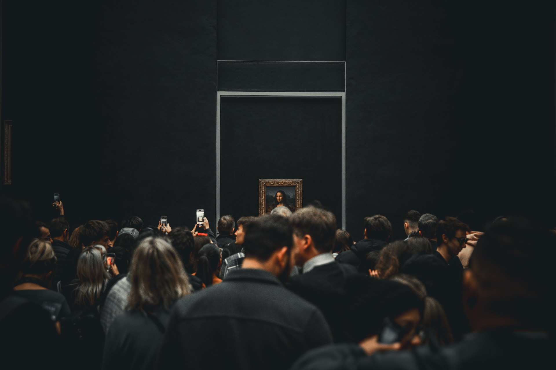Crowd gathered to view painting in dark museum hall